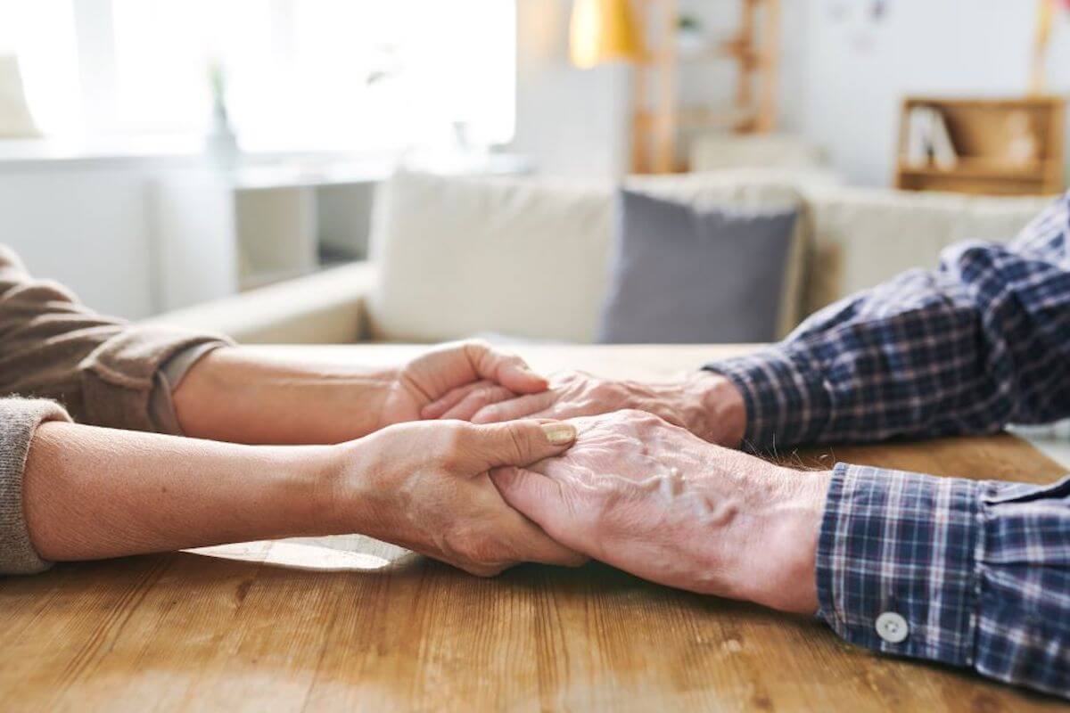 Man and woman holding hands on table-Tips for new family caregivers