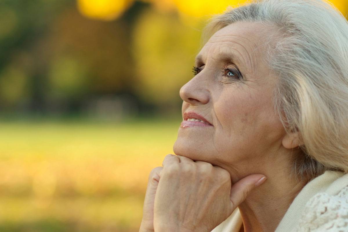 Older woman outside, looking off into distance