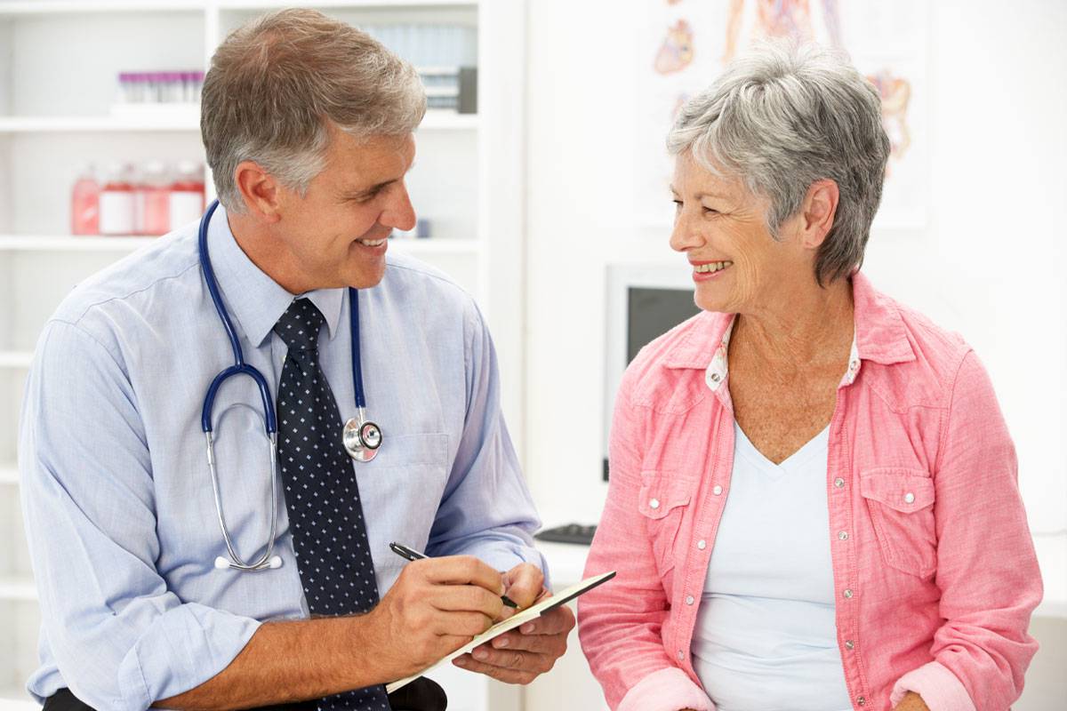 Older woman talking to male healthcare provider, smiling