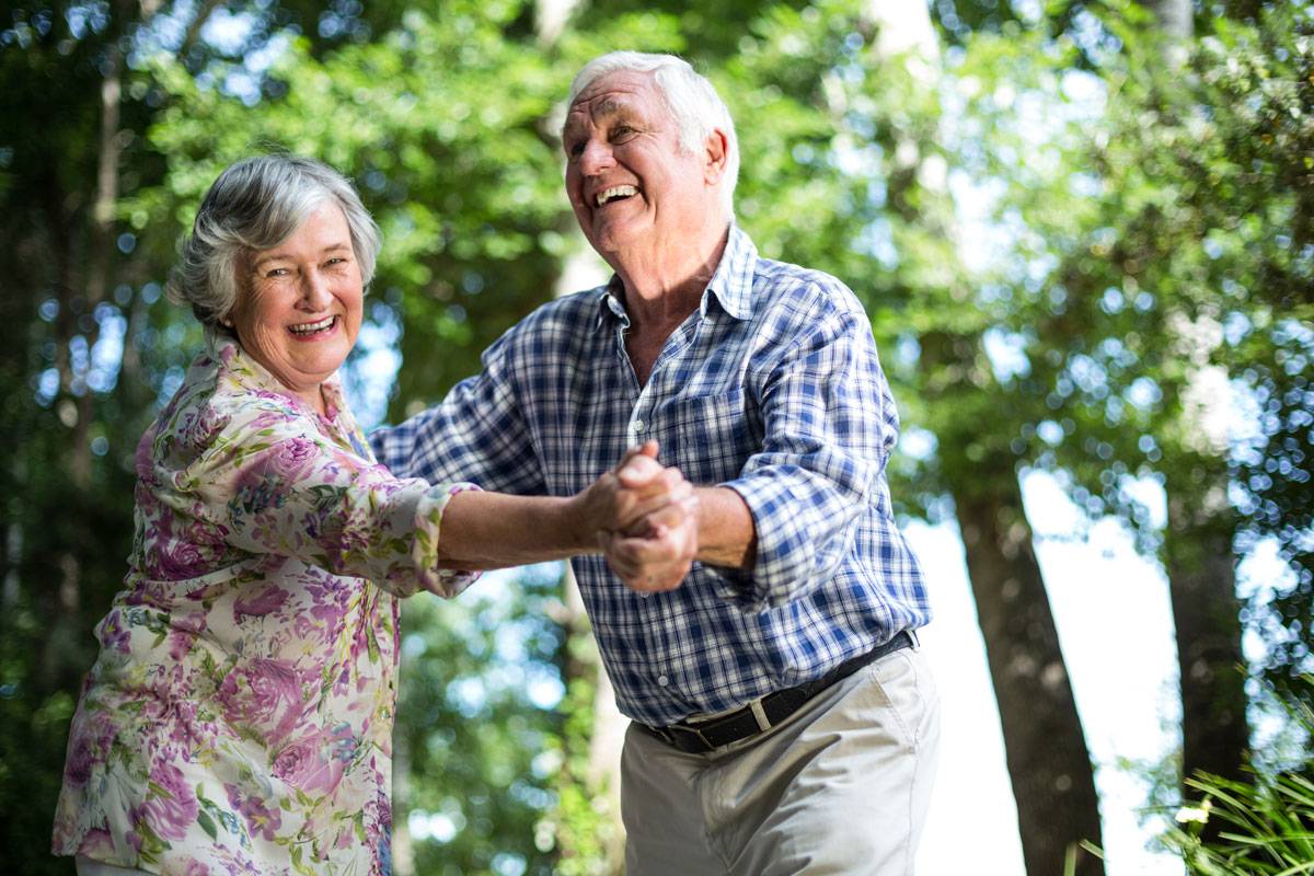 Older couple dancing outside; smiling and laughing