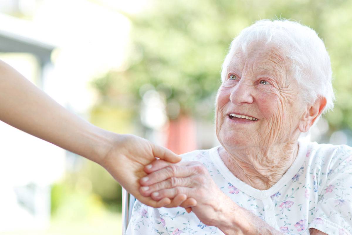 Close up of older woman smiling, holding hand of younger woman