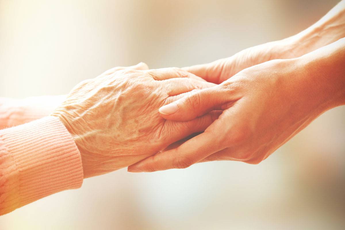 Close up of older woman and younger woman holding hands