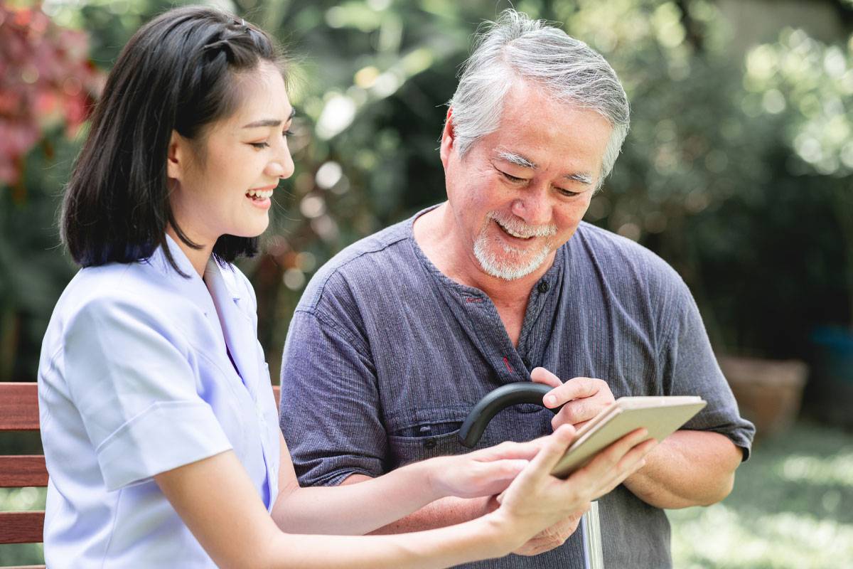 Caregiver and Older Man Outside, Looking at Tablet-Dementia Care & Support in Stuart, Florida