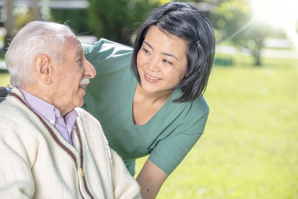 Caregiver Smiling at Older Man in Wheelchair-Assisted Senior Living