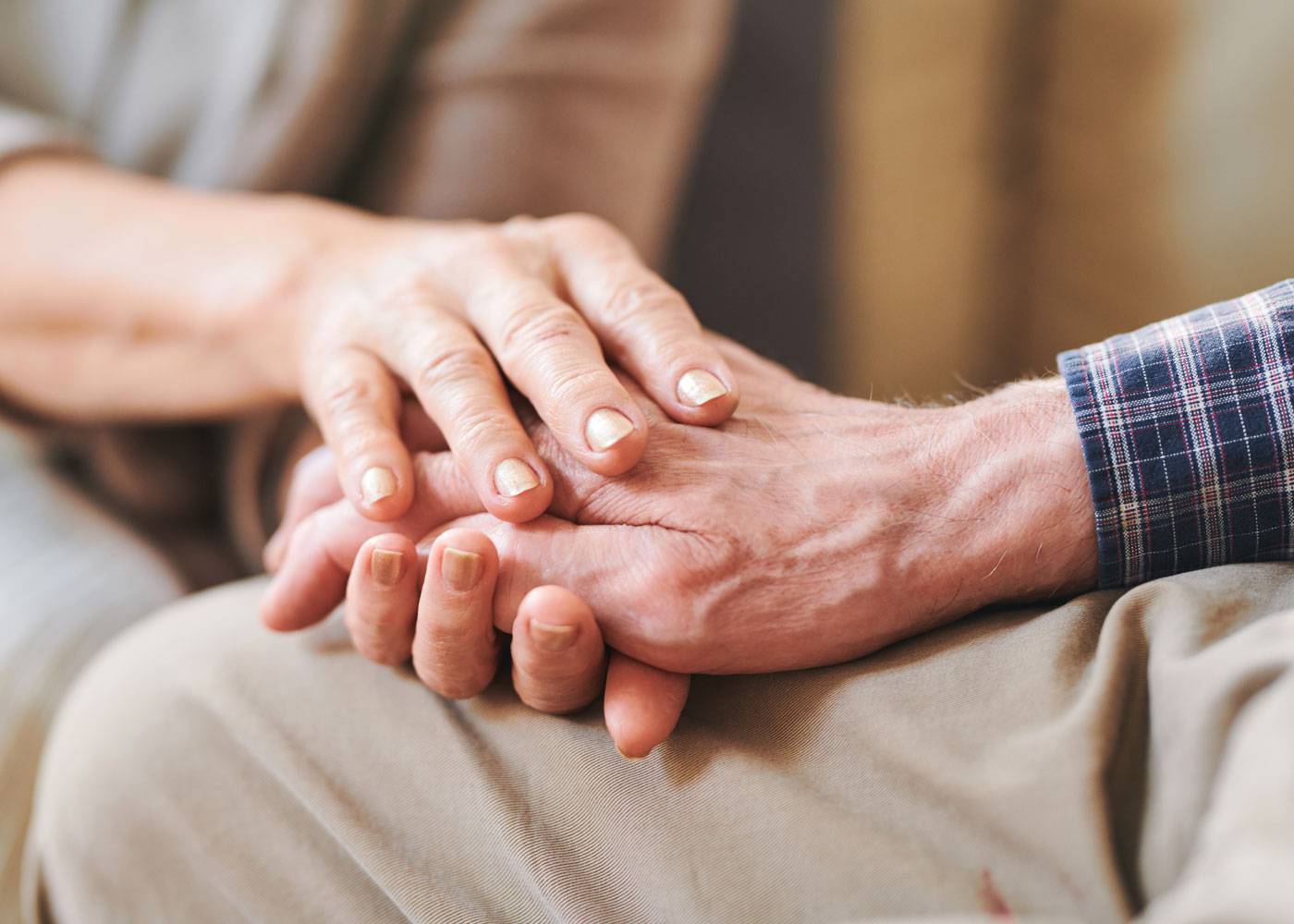 Close up of a caregiver holding the hand of an older man