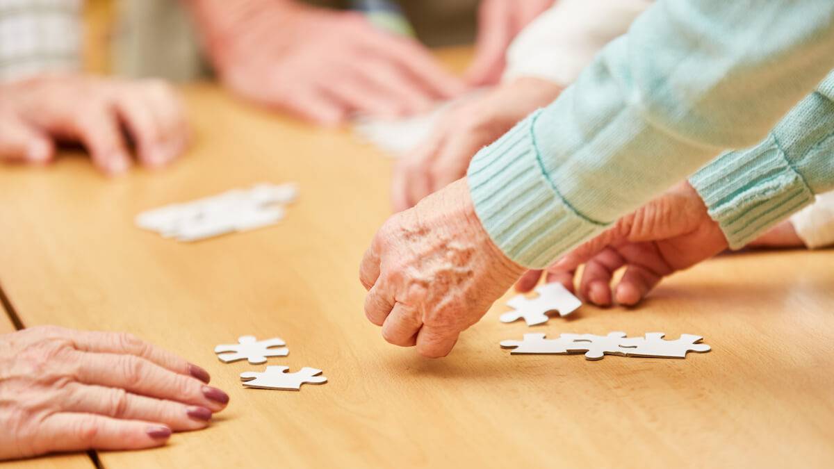 Older Hands Completing Puzzle on Table