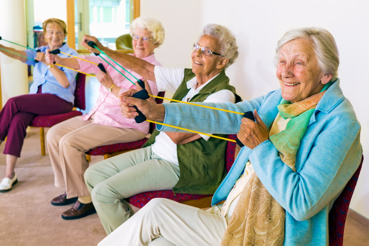 Group of Older Adults Sitting, Using Exercise Bands with their Hands-Mild Dementia Care & Support