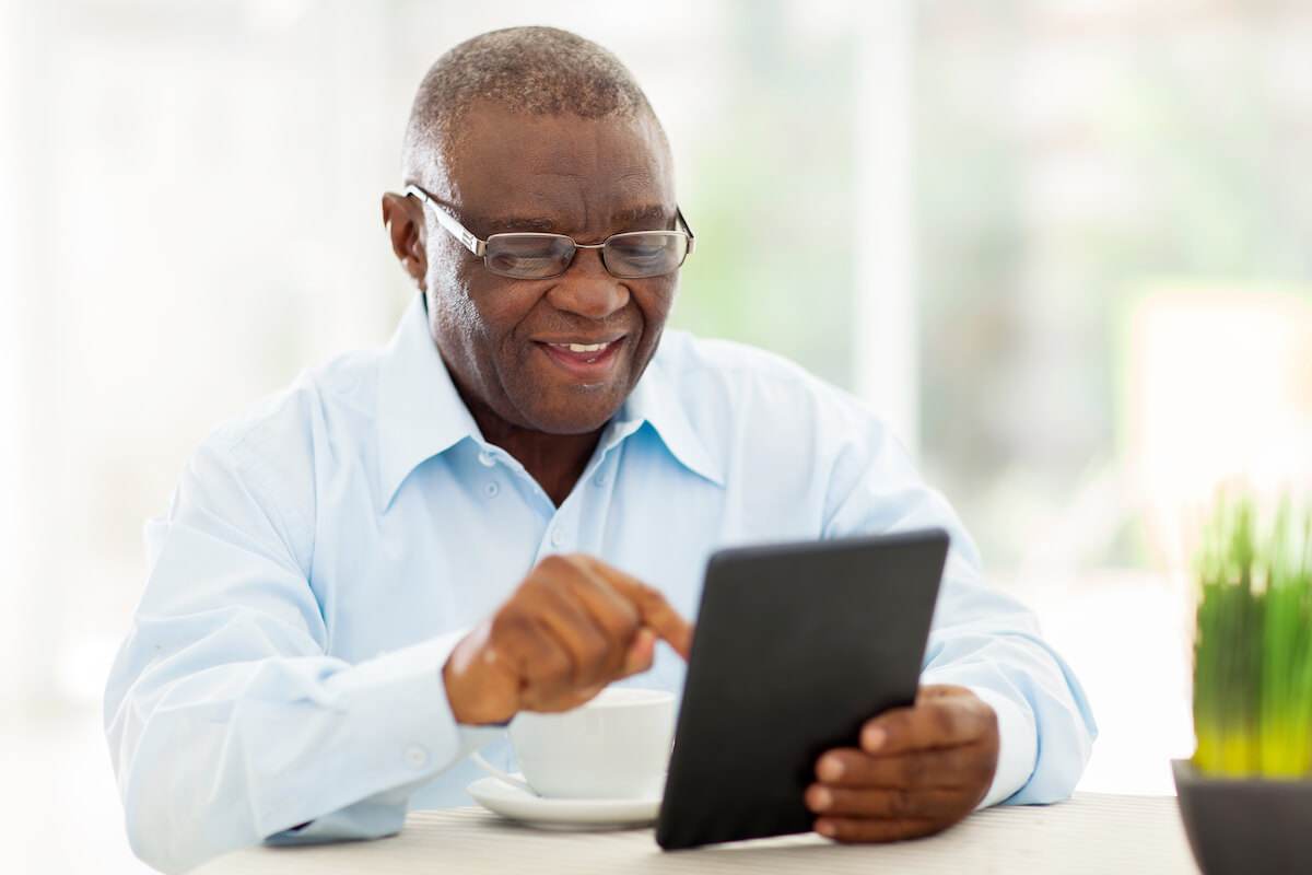 Man Sitting at Table, Using Tablet-Luxury Senior Living in Stuart, Florida