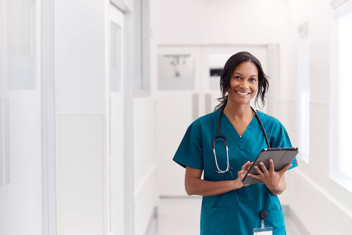 Female healthcare worker smiling, holding tablet-Careers in senior living