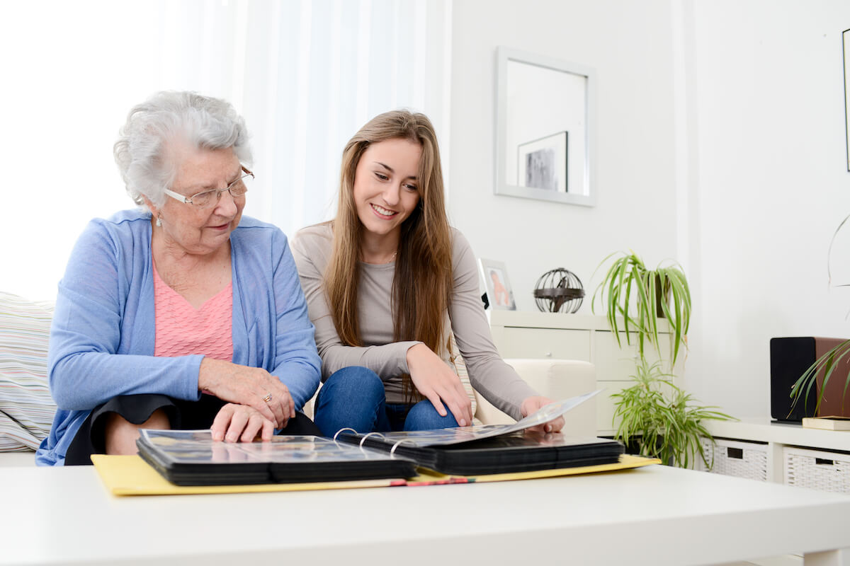Grandmother and granddaughter on couch looking at photo album-Easing transition into memory care