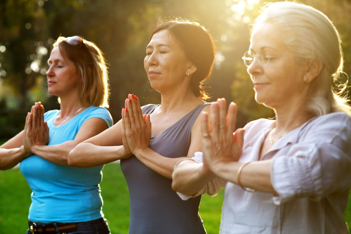 Group of women doing yoga, meditating outside-Guide to yoga for seniors