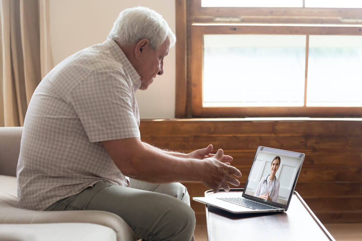 Older man having video call on laptop with female healthcare provider-Telehealth Services