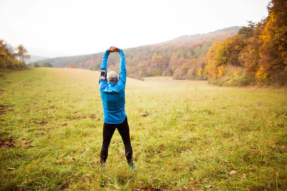Older man stretching, standing in open field, autumn-What is Active Relaxation
