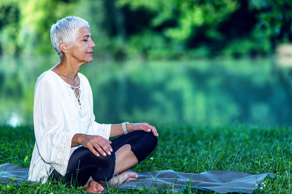 Older woman meditating outside-Tips for Stress Management