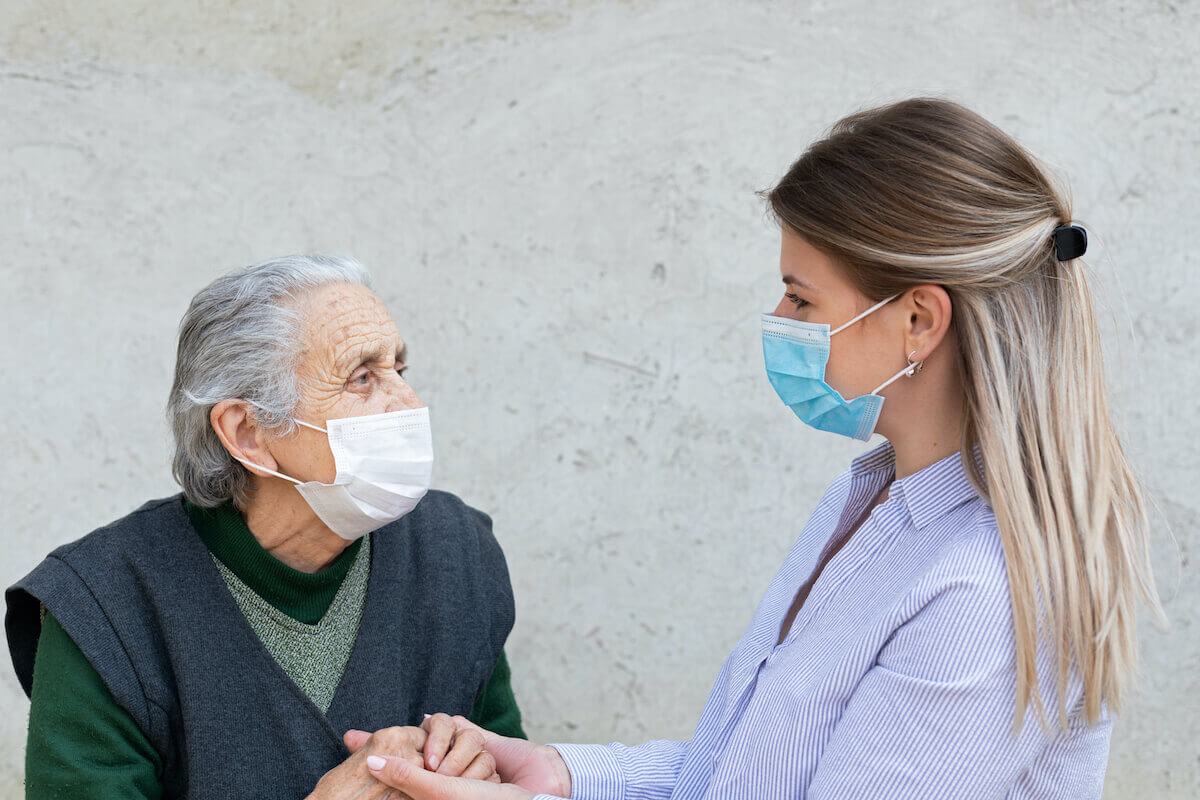 Older woman with younger woman, wearing masks and holding hands-Why work in senior living