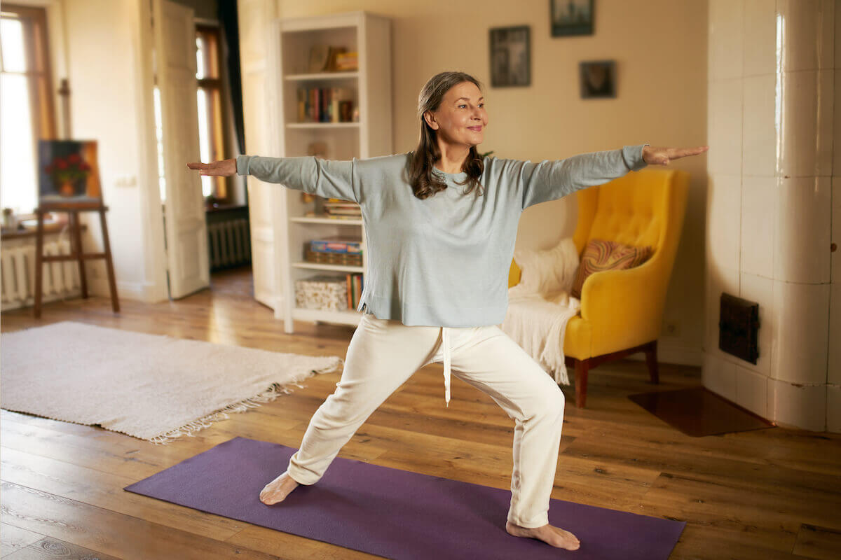 Woman during yoga on mat in living room-Low impact winter exercises