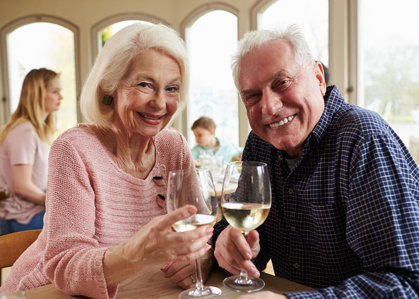 Older couples clinking wine glasses, smiling-Dining at HarborChase of McKinney-Luxury Senior Living in Texas