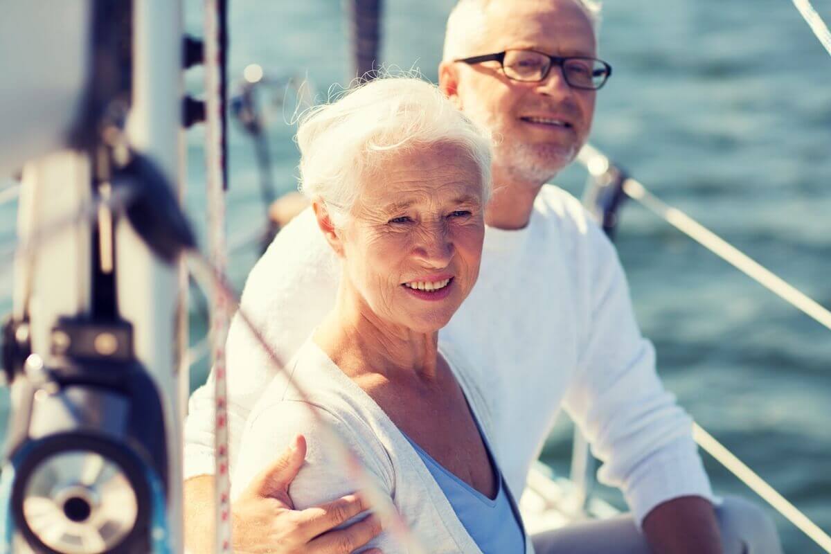 senior-couple-hugging-on-sail-boat-or-yacht-in-HarborChaseSeniorLiving