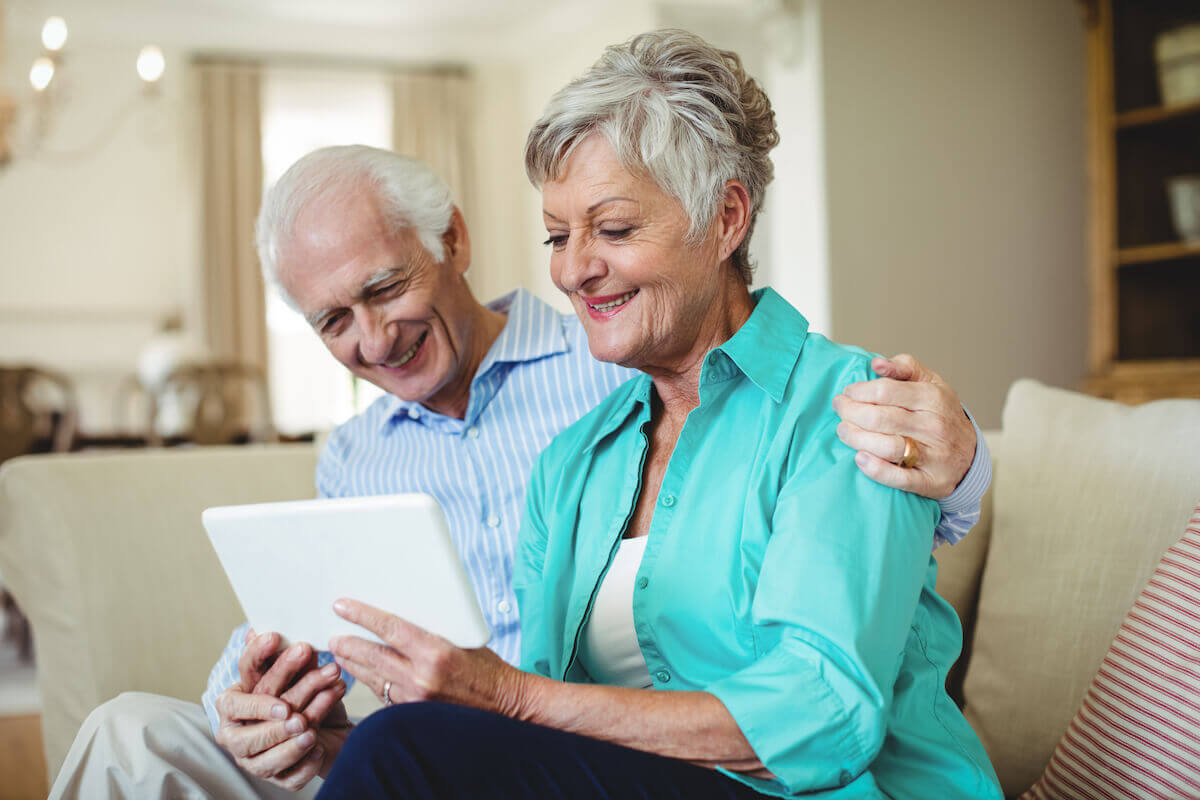 senior-couple-using-digital-tablet-in-living-room-HarborChase Senior Living