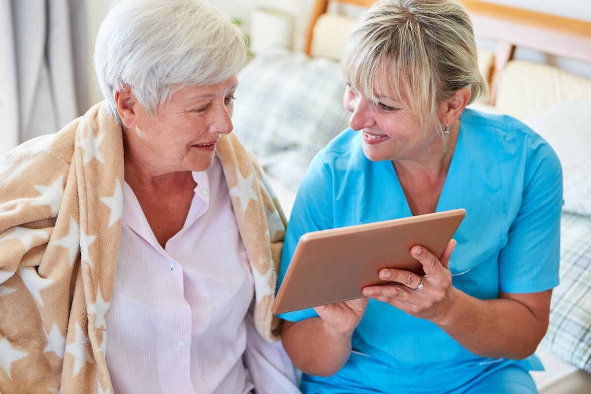 Nurse Helps Senior Woman Video Chat On Tablet Computer In Nursing Home Or At Home-Florida Senior Living