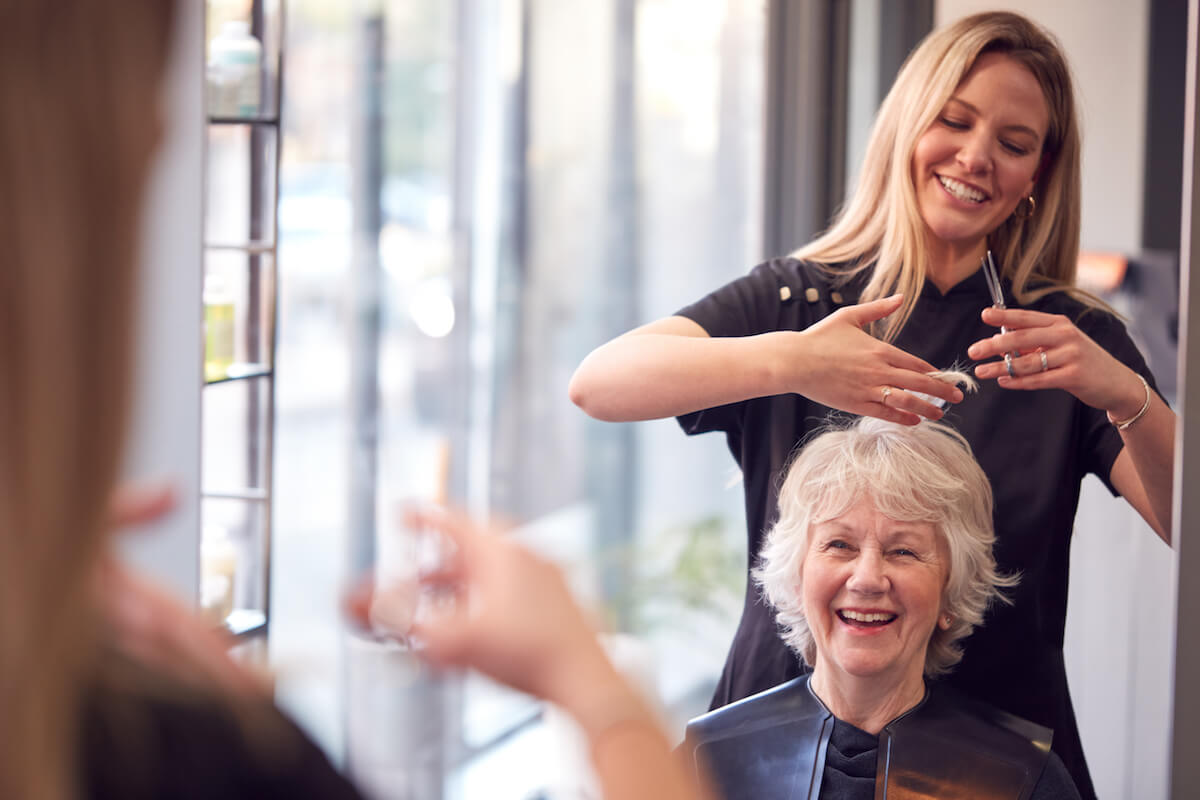 Senior Woman Having Hair Cut By Female Stylist In Hairdressing Salon-Independent living vs living alone