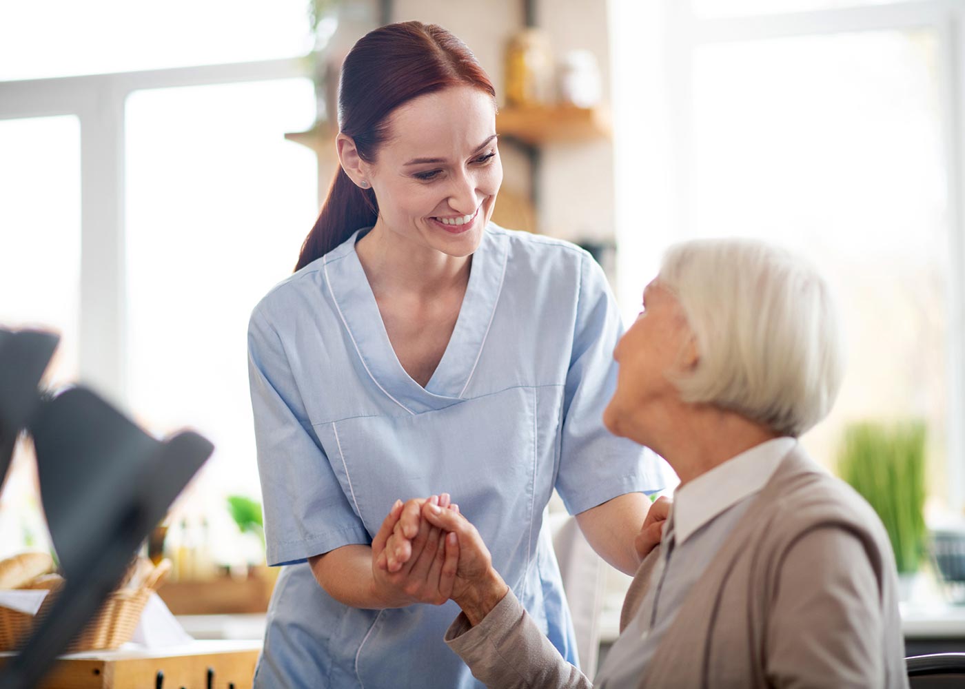 Female caregiver and older woman, holding hands, smiling